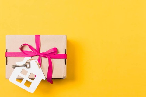 Gift box tied with key house model bright yellow background