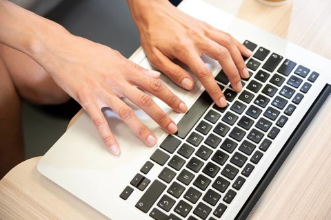 Hand typing laptop top view