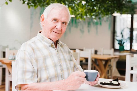 Elderly man drinking tea looking camera