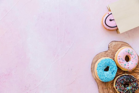 Fresh donuts chopping board near package pink background
