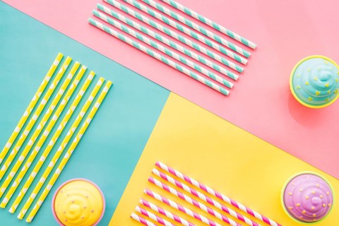 Colored surface with birthday cupcakes straws
