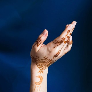 Hand with mehndi near blue textile