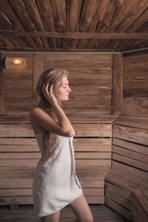 Woman with wet long hair standing hot sauna