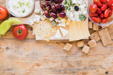 Green chilies pepper tomatoes grapes crisp bread cheese cubes desk