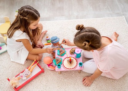 Non binary children playing birthday game with baby dolls
