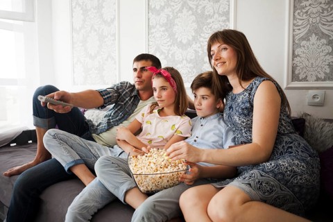 Family eating popcorn during watching television home