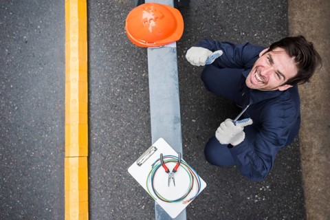 High angle view happy male electrician showing thumb up workplace