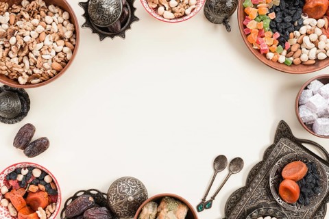 Dried fruits nuts dates lukum baklava metallic bowl white backdrop with space center