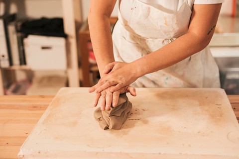 Woman s hand kneading clay table