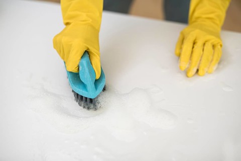 High angle woman with cleaning gloves using brush