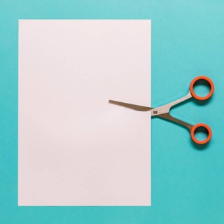 Scissors cutting paper blue background