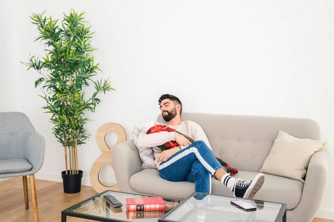 Young handsome man sleeping sofa with his baby hand home