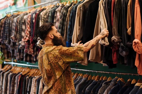 Young man looking shirt hanging rail inside clothing shop
