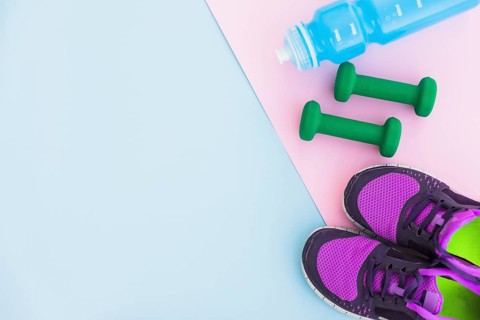 Water bottle sport shoes dumbbells pink backdrop blue background