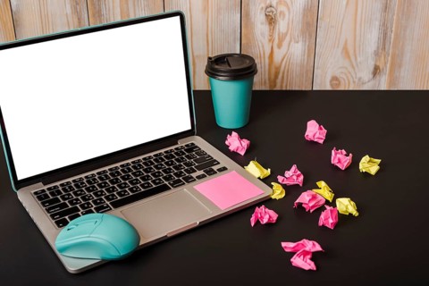 Turquoise mouse adhesive note takeaway cup crumpled paper laptop showing white screen display black background