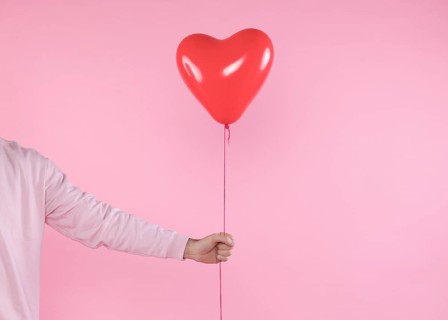 Person holding red balloon with twist