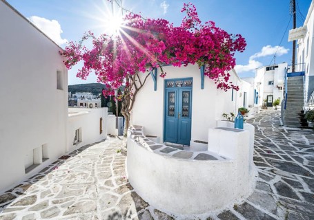 White Cycladic house with blue door and pink bougainvillea