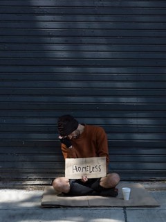 Homeless man hiding his face asking money long view
