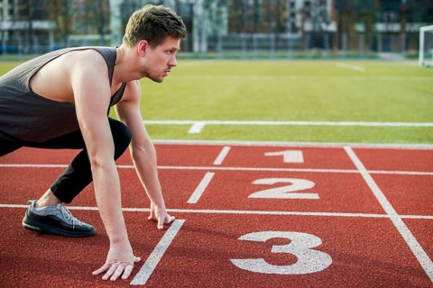 Young male athlete ready run taking position start line