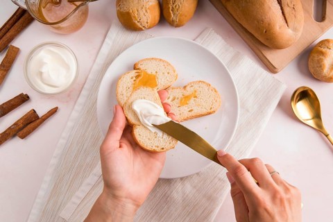 Top view woman spreading cream cheese bread