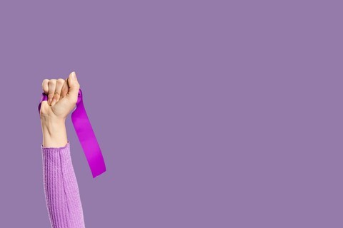 Woman s hand holding violet ribbon copy space