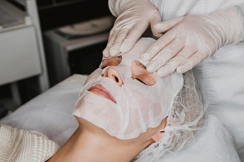 Young woman getting skin mask treatment spa