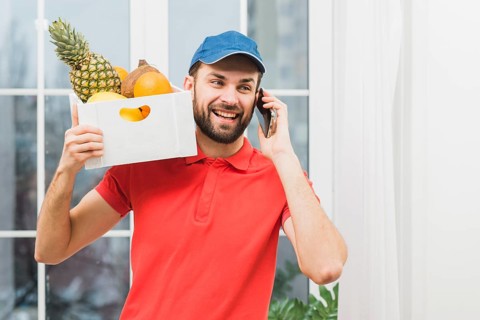 Courier with fruits speaking phone