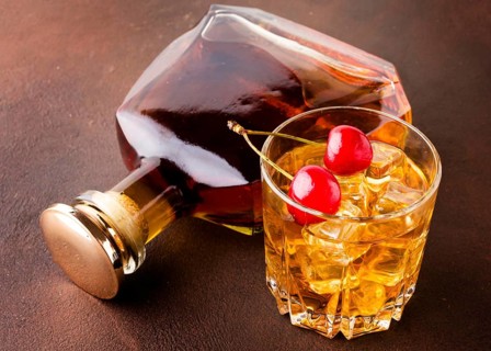 High angle whiskey glass cherries with bottle