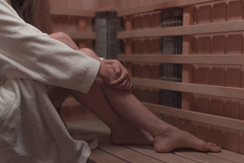 Low section woman sitting wooden bench sauna