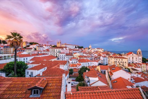 View of Lisbon famous view from Miradouro de Santa Luzia tourist viewpoint over Alfama old city district on sunset with dramatic overcast sky. Lisbon