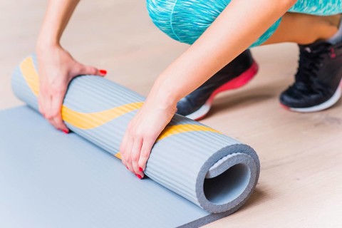 Close up female hand folding yoga mat