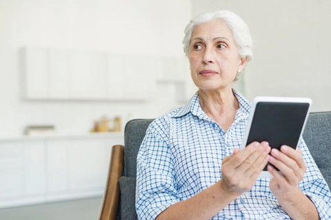 Senior woman holding digital tablet looking away