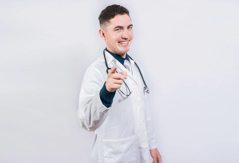 Handsome doctor pointing at the camera. Friendly and smiling doctor pointing at you