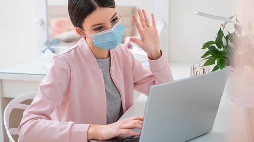 Young business woman working from home wearing mask