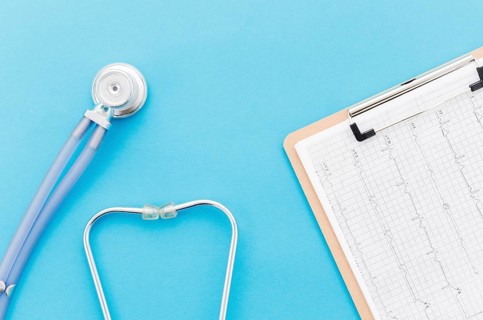 Overhead view stethoscope near ecg paper graph report blue backdrop