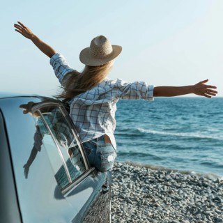 Blonde woman with hat standing out car window