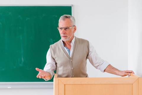 Senior male professor explaining lesson near chalkboard