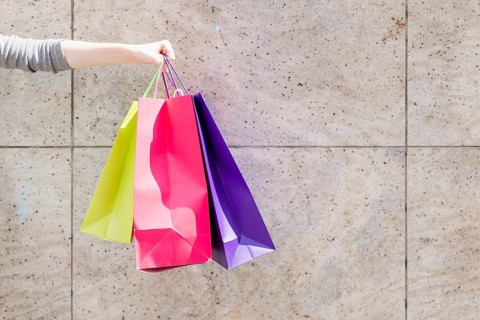 Close up woman s hand with colorful shopping bags front wall