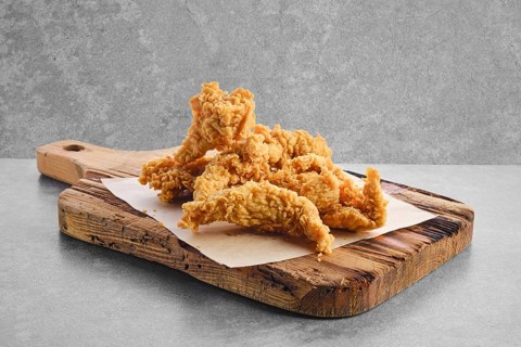 Deep fried chicken nuggets in breading on parchment paper
