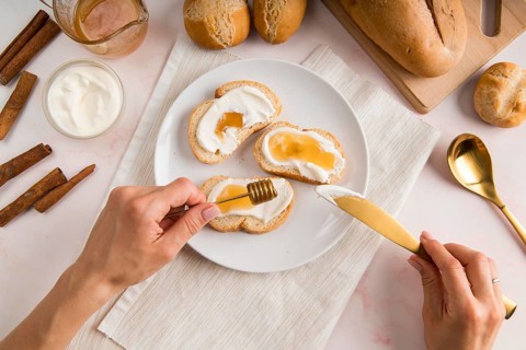Flat lay woman spreading cream cheese bread