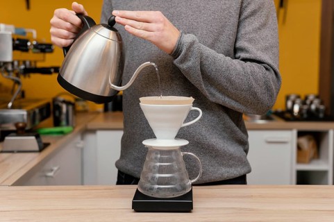 Front view male barista pouring hot water coffee filter