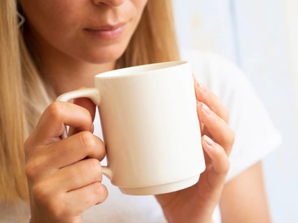 Young woman holding white cup