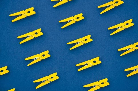 Flat lay yellow clothes pins blue background
