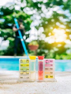 Pool water PH tester kit on the edge of the swimming pool. Tester kit to measure chlorine and ph in swimming pools