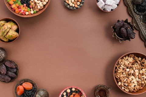 Metallic earthen bowl dried fruits dates lukum nuts baklava arranged circular shapeover brown background