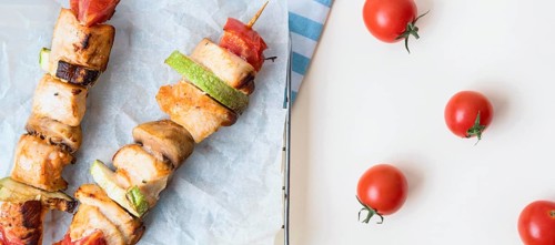 Top view chicken skewers parchment paper with tomatoes