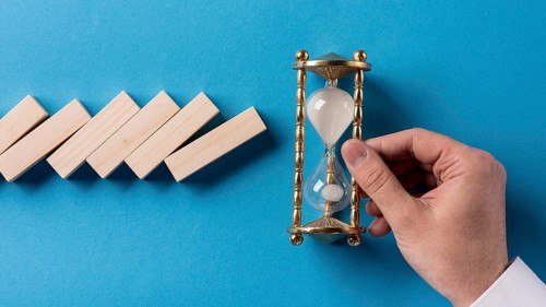 Top view domino pieces with businessman holding hourglass