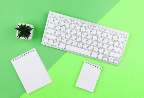 Top view stationery arrangement green background with empty notepads