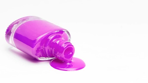 Fallen pink nail polish bottle isolated white surface