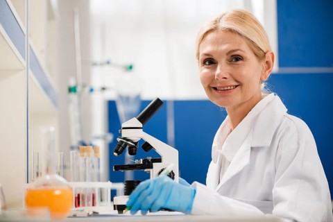 Side view female scientist posing lab with microscope surgical gloves